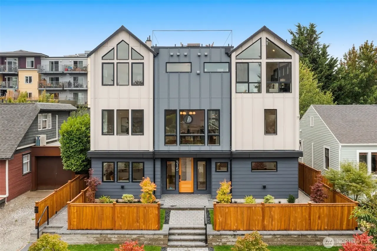 Completed modern two-tone infill home with gabled roofline, board-and-batten siding and cedar fencing